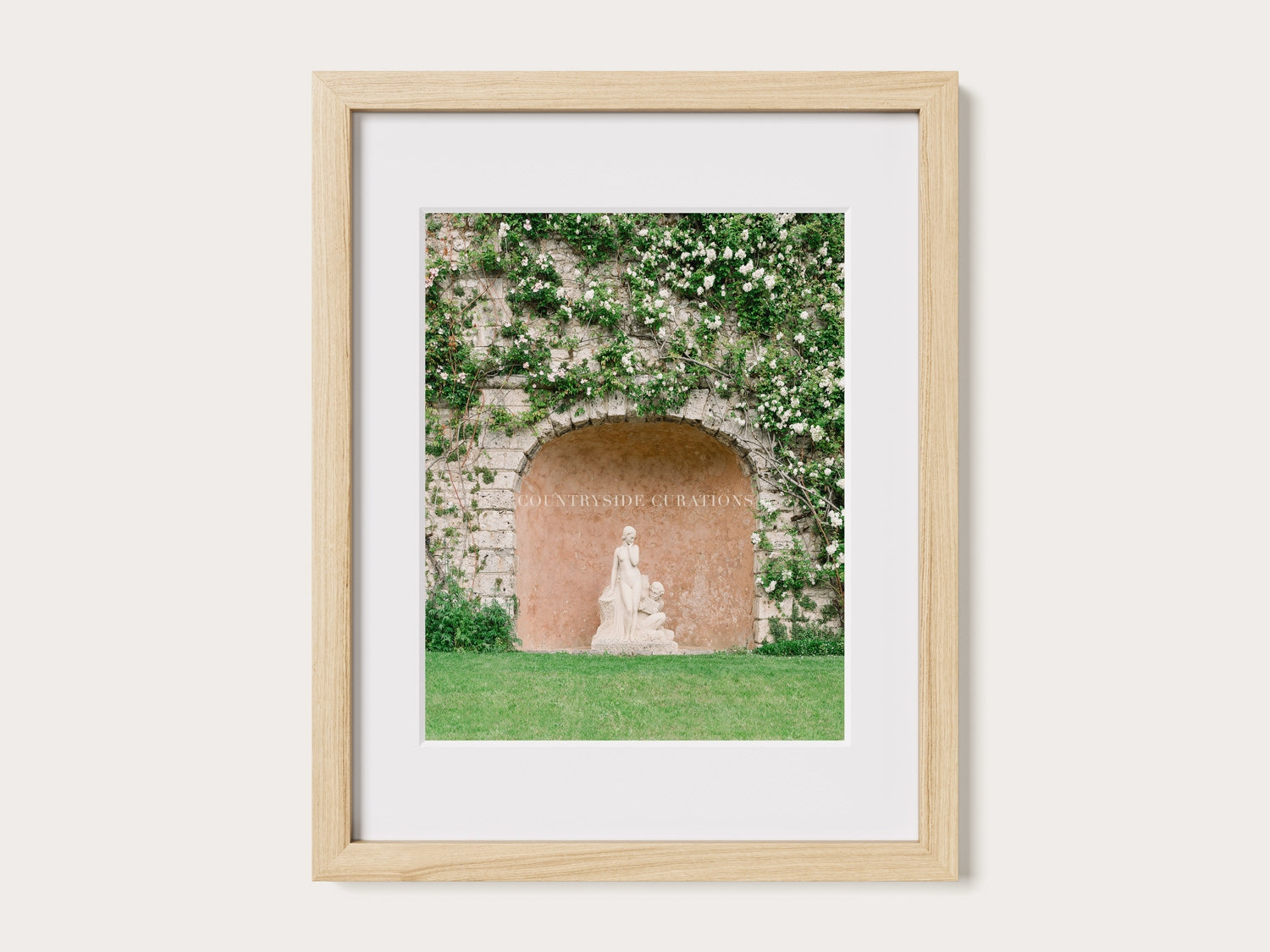 Romantic garden scene with a statue in a stone niche surrounded by greenery and delicate blooms in soft natural light.