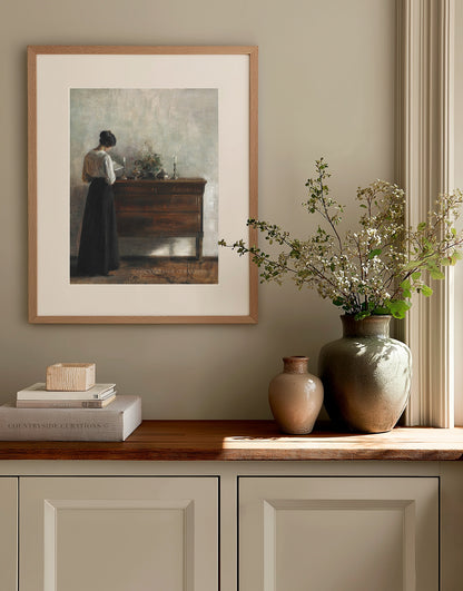 Framed vintage artwork on a wall above a wooden cabinet with decorative items.